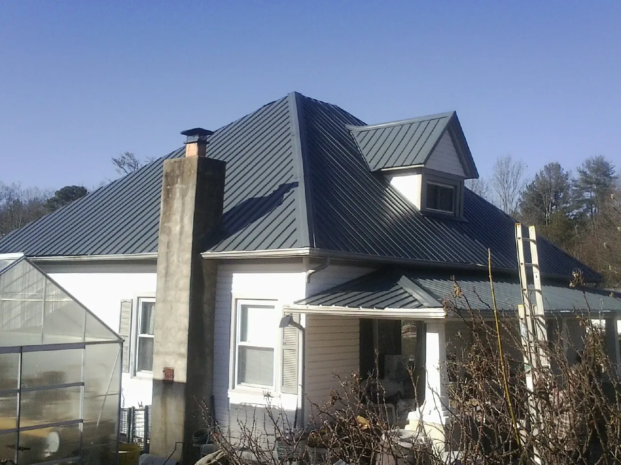 Dark blue standing seam metal roof on a white farmhouse with dormer — Slate & Tile Roof Repair by Roofing Brothers in Allison Park