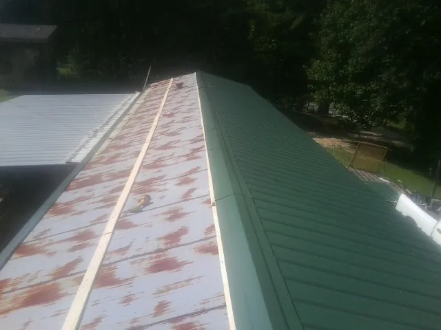 Old rusted panels beside newly installed green metal roofing — Wind Damage Roof Repair by Roofing Brothers in Allison Park