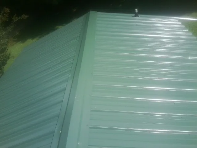 New green metal panels meeting at the ridge of a roof — Flat Roof Repair work by our crew in Allison Park