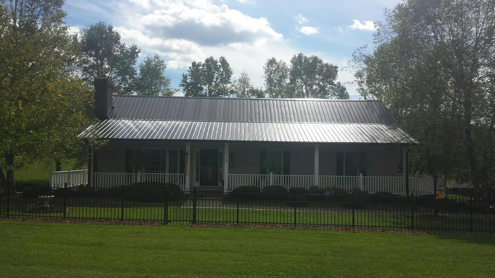Gray metal roof on a brick ranch with a full width front porch — Gutter Guard Installation work by our crew in Allison Park