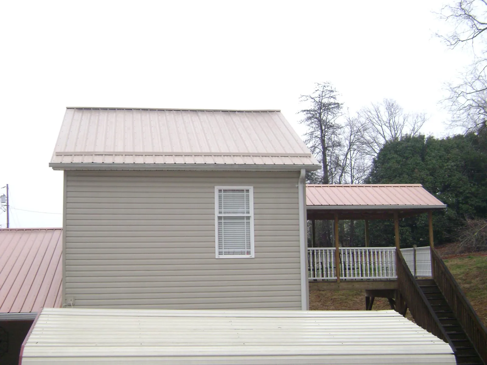 Tan metal roofs on a two story addition and attached porch, from a Roof Replacement job in Allison Park