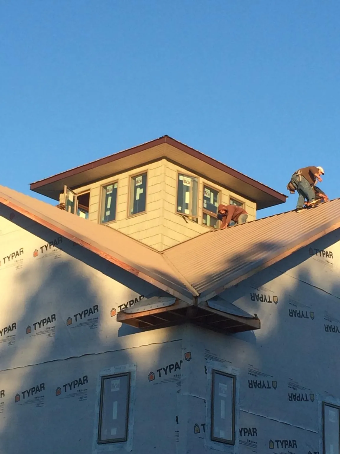 Roofers working around a rooftop cupola on a new metal roof at sunset — Roof Waterproofing in Allison Park by Roofing Brothers